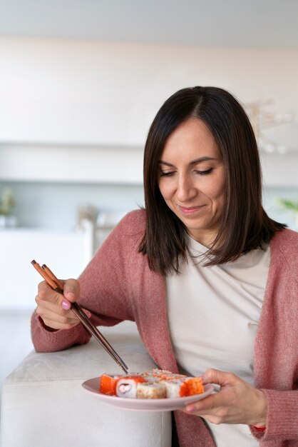 Mujer de tiro medio comiendo sushi en casa