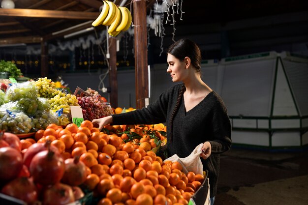 Mujer de tiro medio comprando mandarina