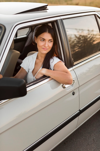 Mujer de tiro medio conduciendo coche viejo