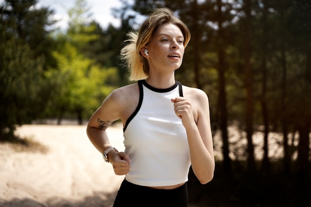 Mujer de tiro medio corriendo con auriculares