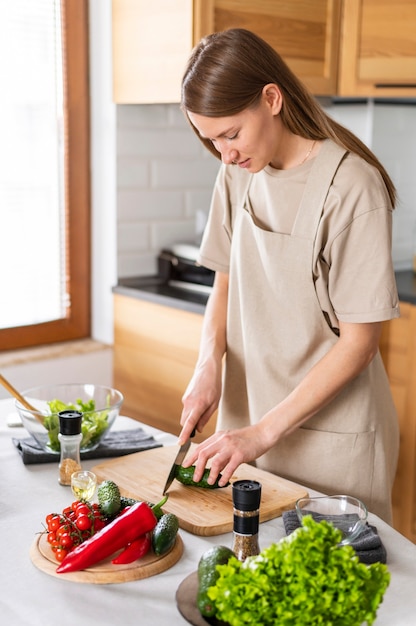 Mujer de tiro medio cortando pepino