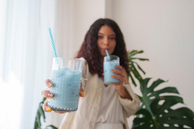 Mujer de tiro medio disfrutando de matcha azul en casa