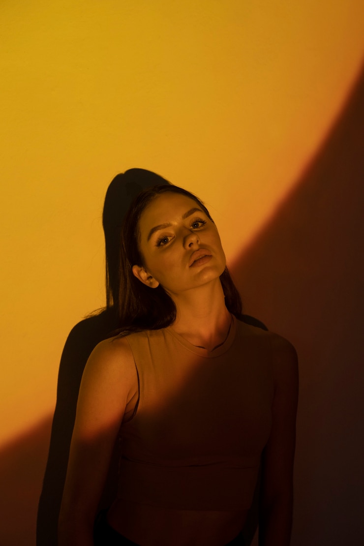 Foto gratuito mujer de tiro medio disparando con luz amarilla.