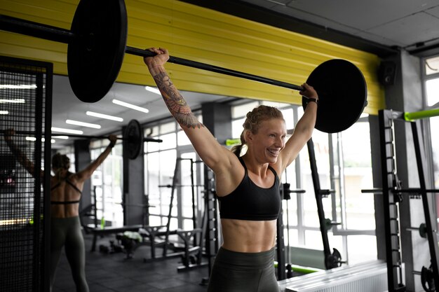 Mujer de tiro medio entrenando con mancuerna