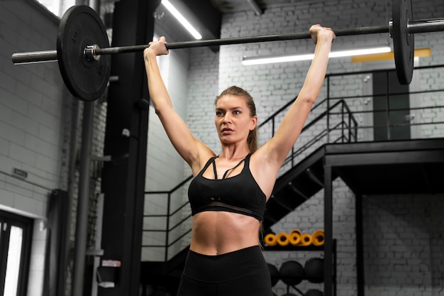 Mujer de tiro medio entrenando con mancuerna