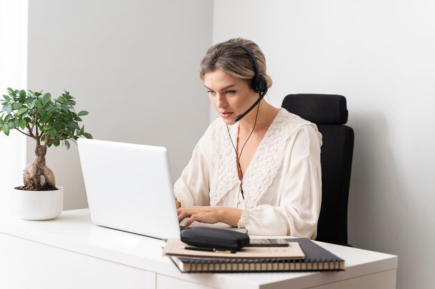 Mujer de tiro medio escribiendo en la computadora portátil