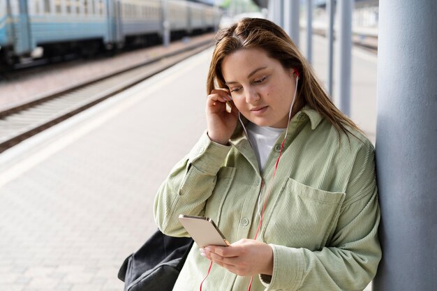 Mujer de tiro medio en la estación de tren