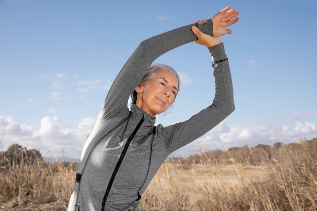 Mujer de tiro medio estirando al aire libre