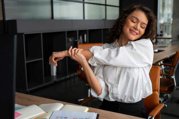 Mujer de tiro medio estirando en el trabajo