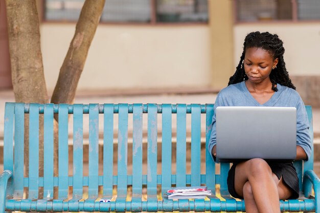 Mujer de tiro medio estudiando con portátil