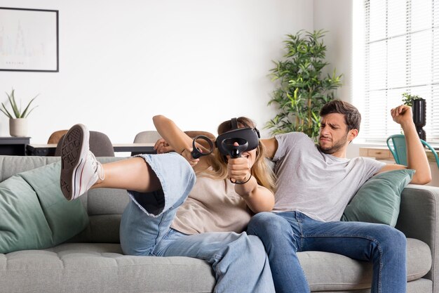 Mujer de tiro medio con gafas de realidad virtual en el sofá