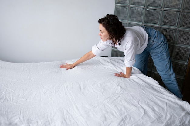 Mujer de tiro medio haciendo la cama