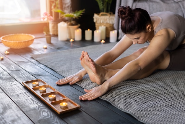 Mujer de tiro medio haciendo yoga en el interior