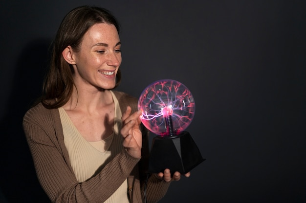 Mujer de tiro medio interactuando con una bola de plasma