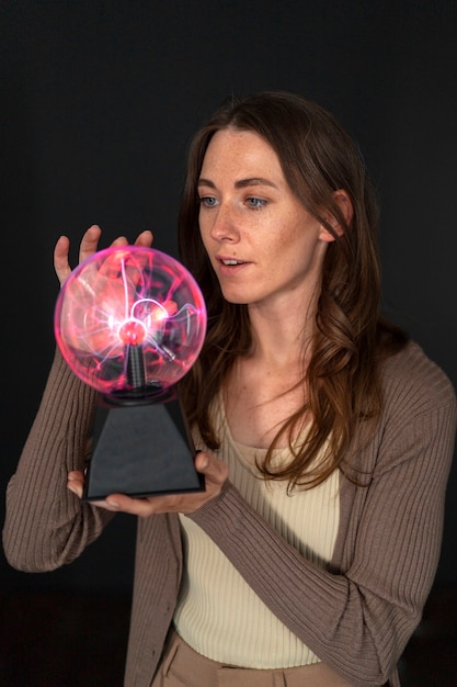 Mujer de tiro medio interactuando con una bola de plasma