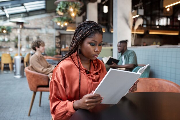 Mujer de tiro medio leyendo en la cafetería