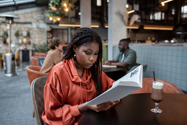 Foto gratuita mujer de tiro medio leyendo en la cafetería