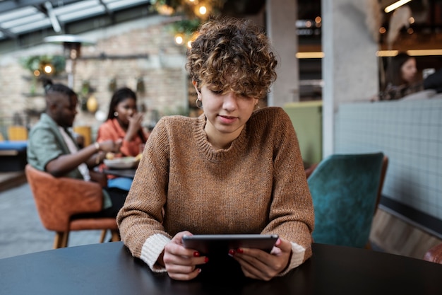 Mujer de tiro medio leyendo en la cafetería