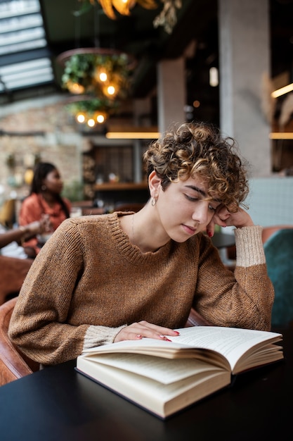 Foto gratuita mujer de tiro medio leyendo en la cafetería