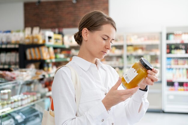 Mujer de tiro medio leyendo la etiqueta en la tienda