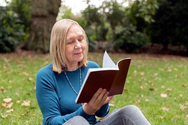 Mujer de tiro medio leyendo en la naturaleza