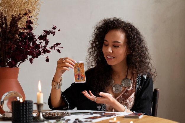 Mujer de tiro medio leyendo tarot en la mesa