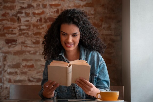 Mujer de tiro medio con libro en cafetería.