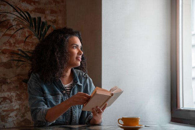 Mujer de tiro medio con libro en cafetería.