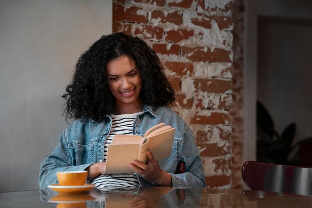 Mujer de tiro medio con libro en cafetería.