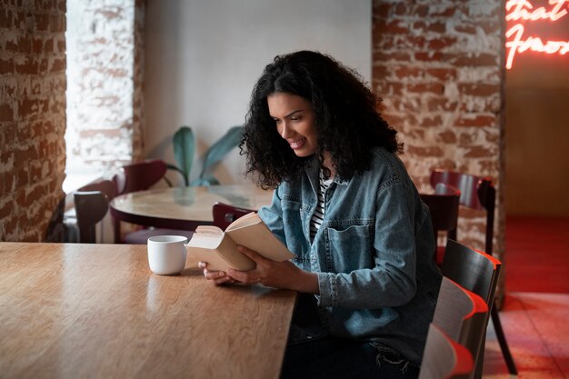 Mujer de tiro medio con libro en cafetería.