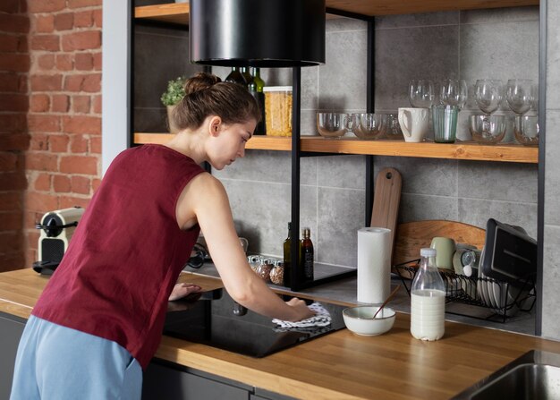 Mujer de tiro medio limpiando cocina