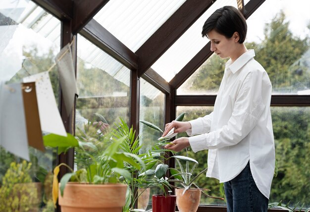 Mujer de tiro medio limpiando la hoja de la planta