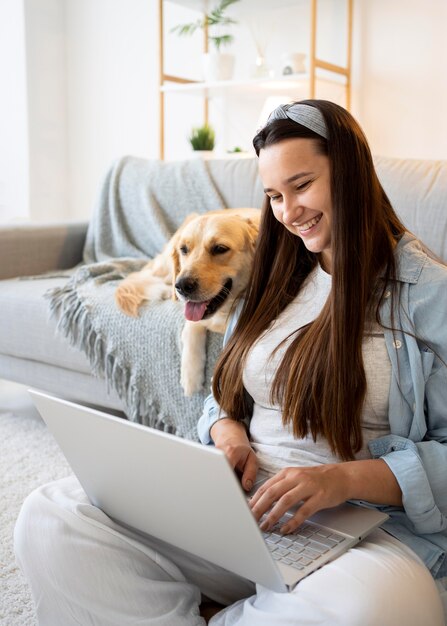 Mujer de tiro medio y lindo perro en casa