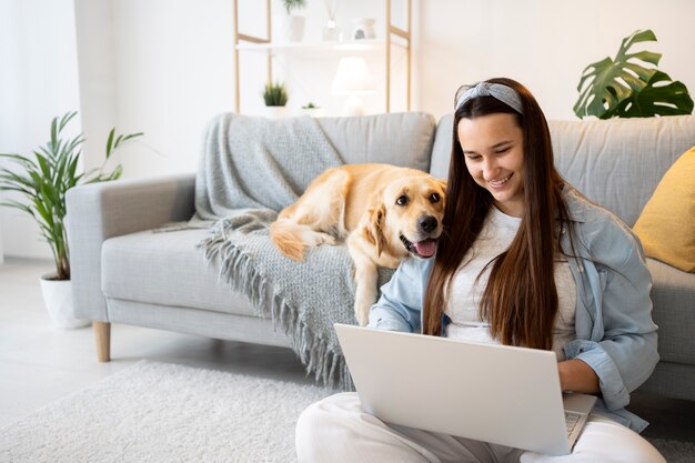 Mujer de tiro medio y lindo perro en el interior