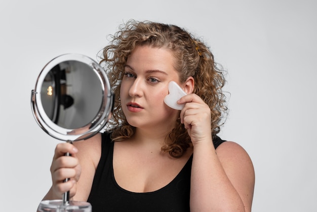 Foto gratuita mujer de tiro medio masajeando la cara con gua sha