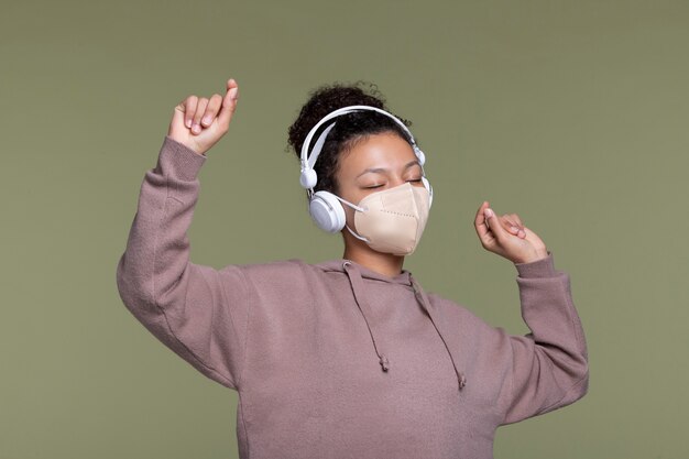 Mujer de tiro medio con máscara y auriculares