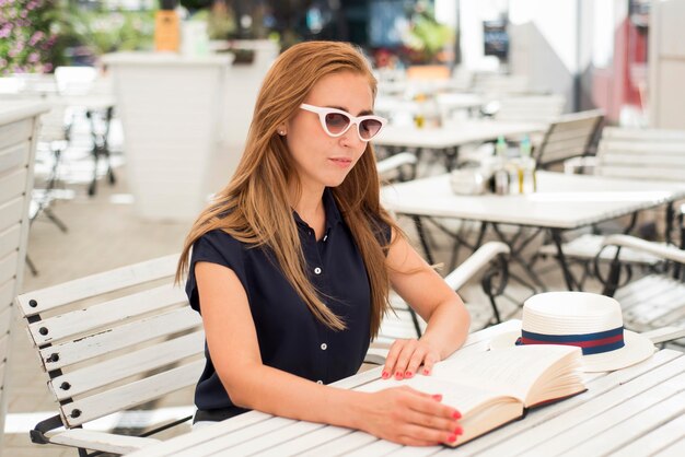 Mujer de tiro medio en la mesa leyendo un libro