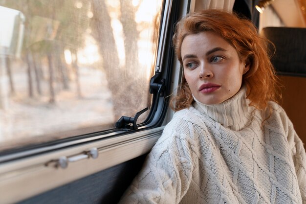 Mujer de tiro medio mirando por la ventana