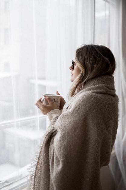 Mujer de tiro medio mirando por la ventana