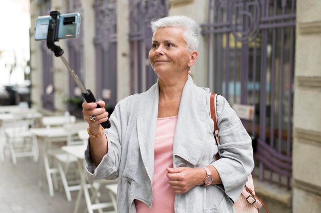 Mujer de tiro medio con palo selfie