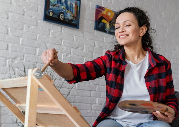 Mujer de tiro medio pintando en casa