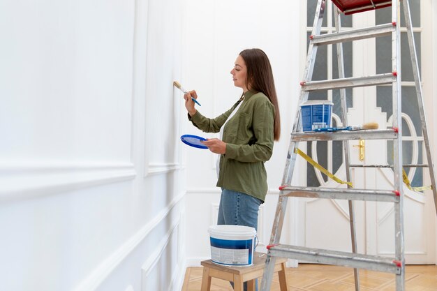 Mujer de tiro medio pintando la pared en casa