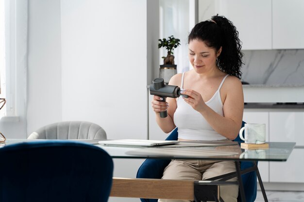 Mujer de tiro medio con pistola de masaje