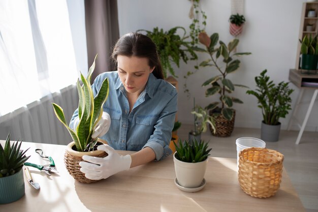 Mujer de tiro medio con planta en casa.