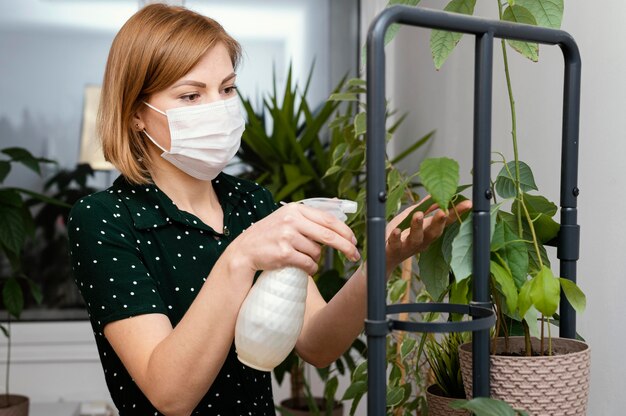 Mujer de tiro medio con planta de riego de máscara