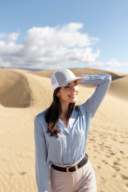 Mujer de tiro medio posando en el desierto con gorra de camionero