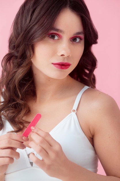 Mujer de tiro medio posando con lima de uñas