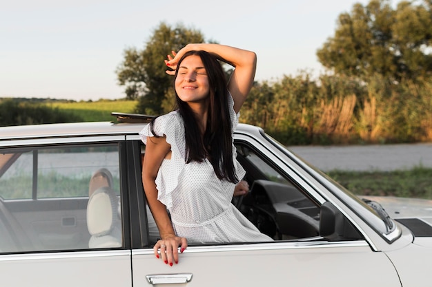 Mujer de tiro medio posando por la ventana