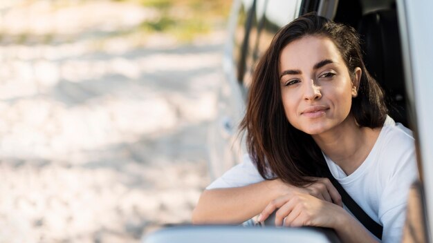 Mujer de tiro medio posando en la ventanilla del coche