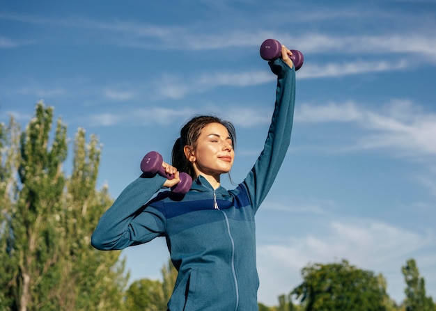 Mujer de tiro medio practicando con pesas